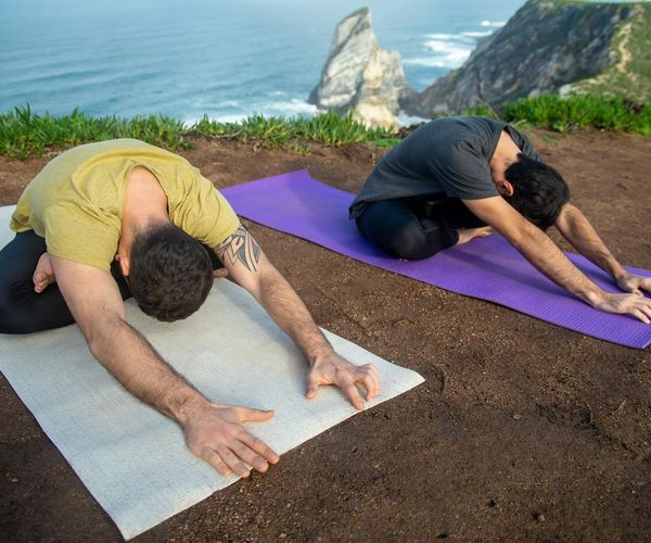 A focused man doing a dynamic stretching exercise outdoors with a natural background.