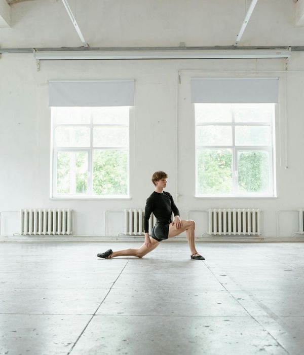 Man performing a bodyweight exercise in a minimalist, light-filled studio.